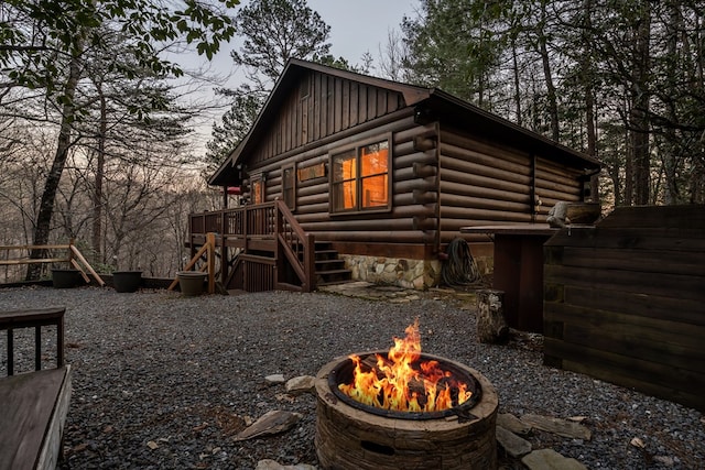 view of side of property with board and batten siding, a fire pit, and log exterior