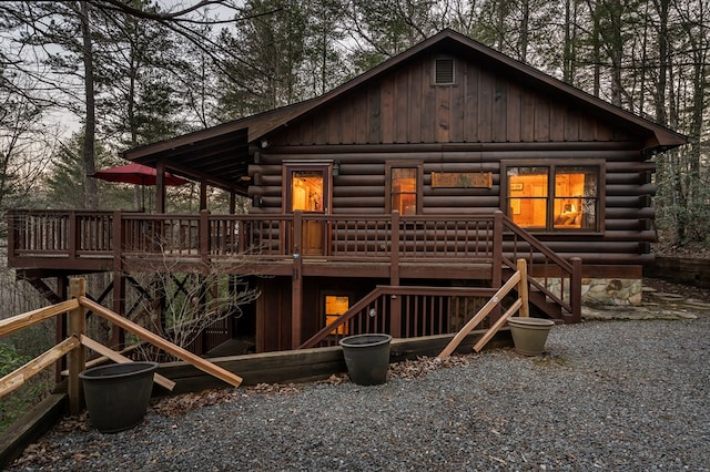 back of property featuring stairway, log siding, and a wooden deck