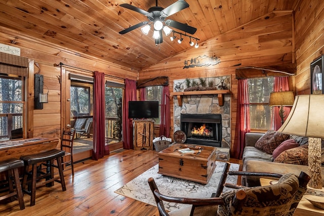 living room with wooden walls, wood ceiling, hardwood / wood-style floors, vaulted ceiling, and a fireplace