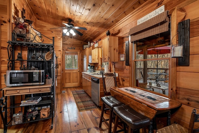 kitchen with lofted ceiling, wooden ceiling, wooden walls, stainless steel appliances, and wood-type flooring