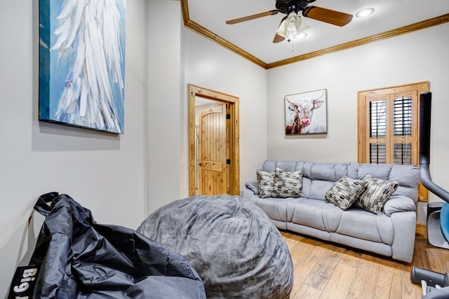 living room with a ceiling fan, ornamental molding, and wood finished floors