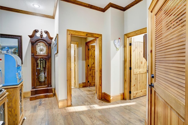 hall with crown molding, baseboards, and light wood-type flooring