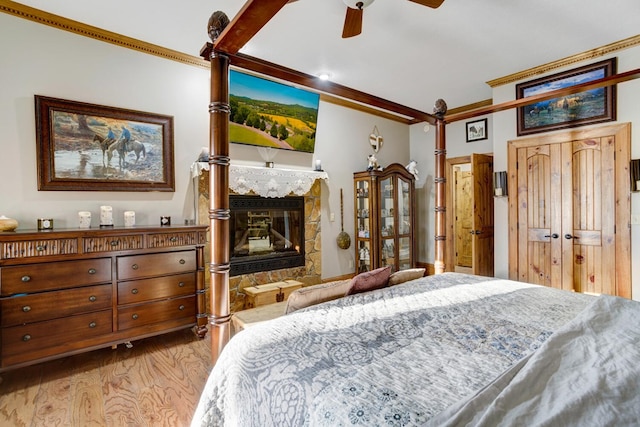 bedroom featuring crown molding, a glass covered fireplace, and wood finished floors