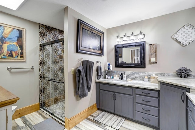 bathroom with wood finished floors, baseboards, a stall shower, and vanity