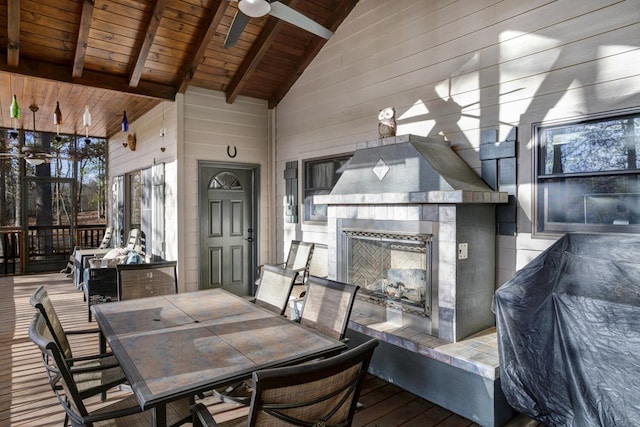 deck with a tiled fireplace, outdoor dining area, and ceiling fan