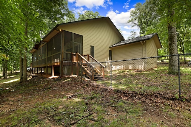 rear view of property featuring a sunroom, fence, and stairway