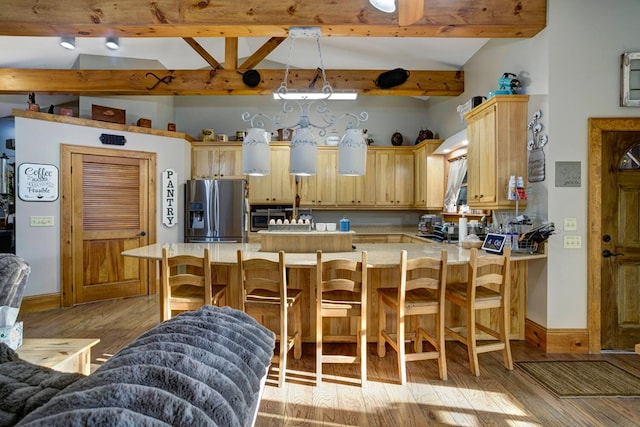 kitchen with light countertops, stainless steel refrigerator with ice dispenser, light brown cabinetry, and a peninsula