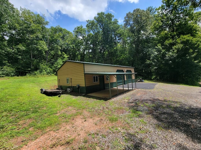 view of home's exterior with a yard, a forest view, and driveway