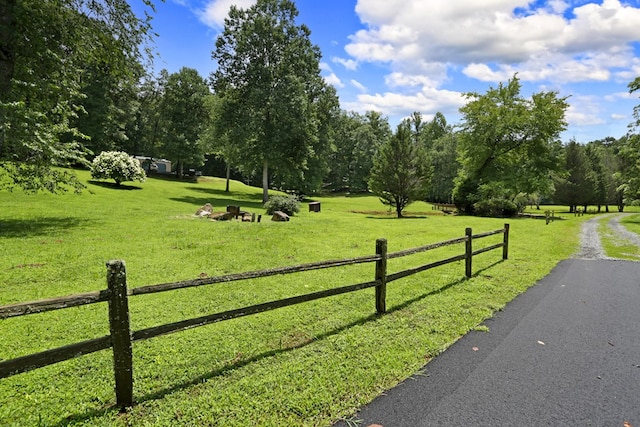 surrounding community with a lawn, fence, and a rural view