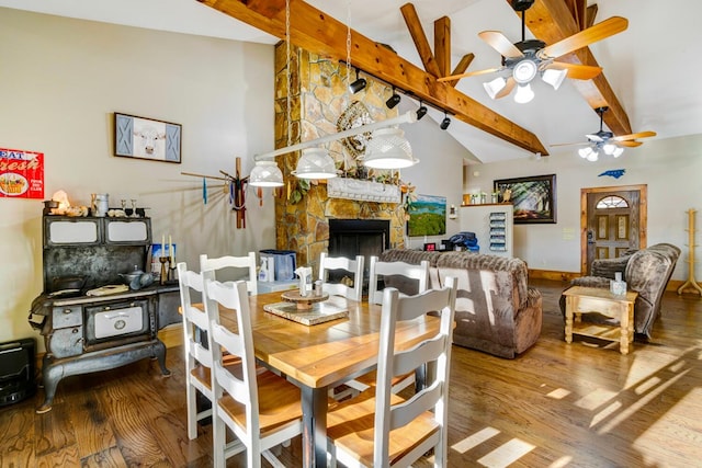 dining room with vaulted ceiling with beams, a ceiling fan, wood finished floors, and a fireplace