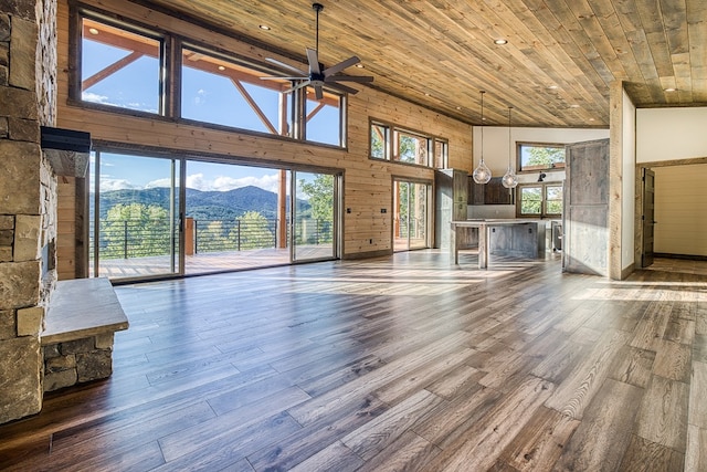 unfurnished living room featuring hardwood / wood-style floors, a mountain view, a high ceiling, ceiling fan, and wood ceiling