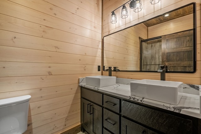 bathroom featuring vanity, wood walls, and toilet