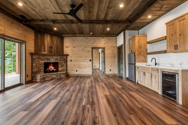 kitchen with stainless steel fridge, wood ceiling, beverage cooler, sink, and wood walls