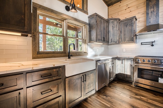 kitchen with appliances with stainless steel finishes, dark brown cabinets, extractor fan, dark wood-type flooring, and sink