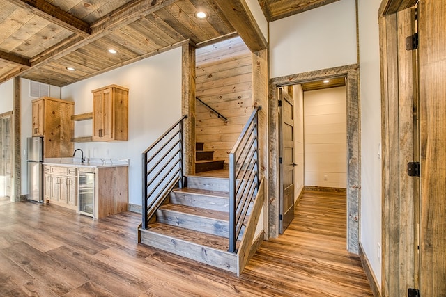 stairway featuring sink, hardwood / wood-style flooring, a towering ceiling, beamed ceiling, and wood ceiling