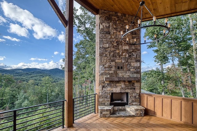 deck with a mountain view and an outdoor stone fireplace