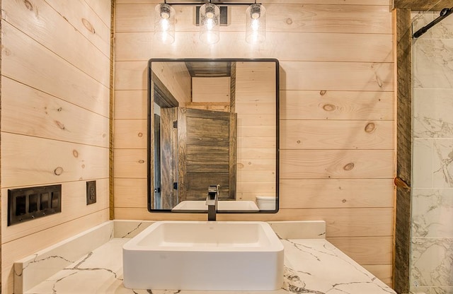 bathroom with wood walls and sink