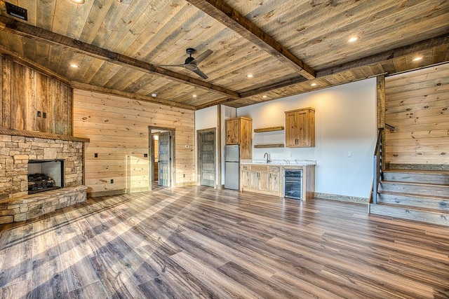 unfurnished living room featuring wood walls, beamed ceiling, beverage cooler, and wood ceiling