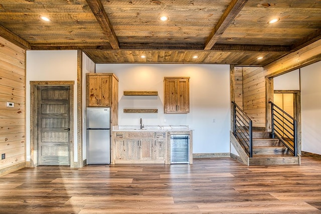 kitchen featuring wood walls, wooden ceiling, and stainless steel refrigerator