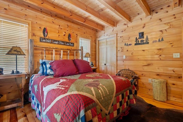 bedroom featuring wooden ceiling, wood walls, a closet, wood-type flooring, and beam ceiling