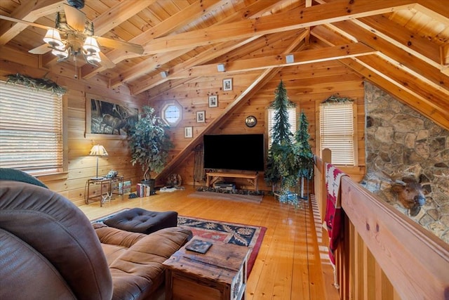 living room with wood-type flooring, wood walls, ceiling fan, and vaulted ceiling with beams