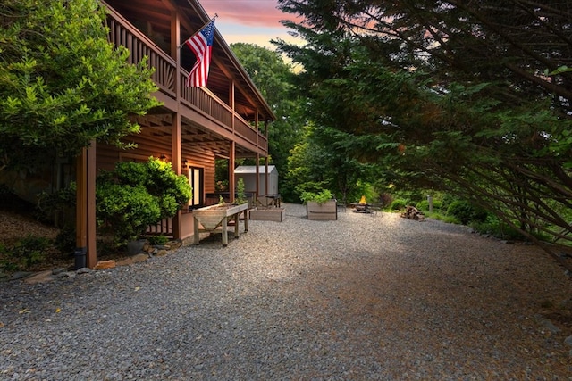 patio terrace at dusk featuring an outdoor fire pit and a shed