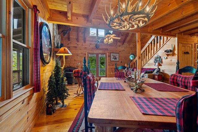 dining room featuring ceiling fan with notable chandelier, wooden walls, wood ceiling, and beam ceiling