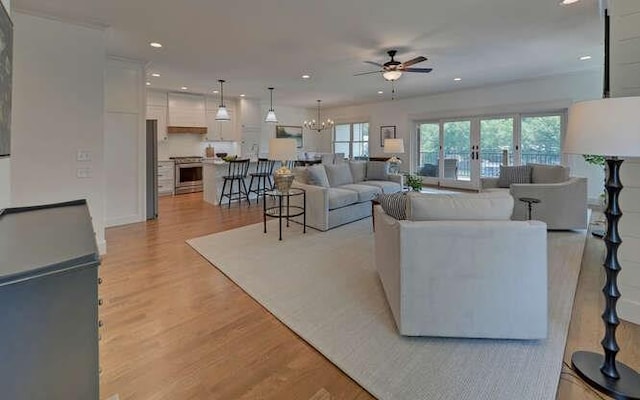 living room with french doors, ceiling fan with notable chandelier, and light wood-type flooring