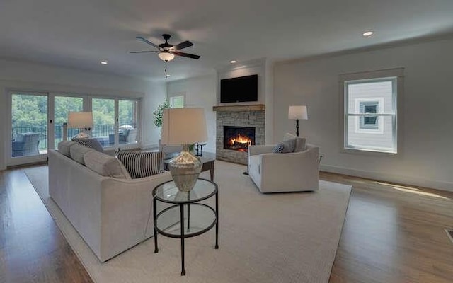 living room featuring a fireplace, light hardwood / wood-style floors, and ceiling fan