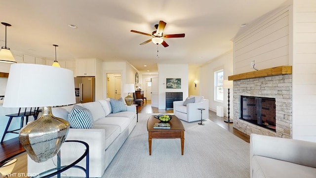 living room featuring a fireplace, light wood-type flooring, and ceiling fan