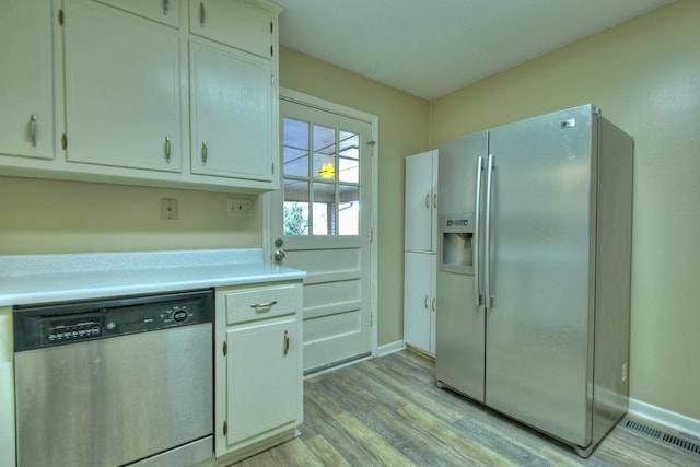 kitchen with stainless steel appliances, light countertops, visible vents, light wood-style floors, and baseboards