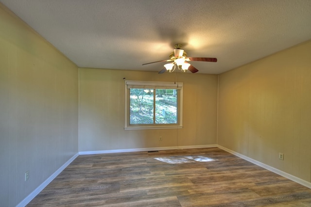 spare room featuring dark wood-style floors, a textured ceiling, visible vents, and a ceiling fan