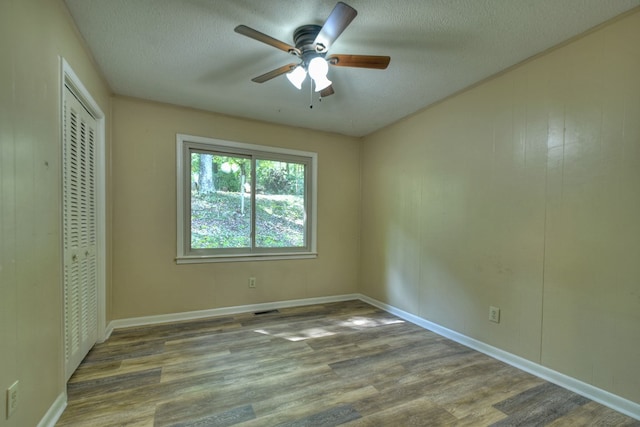 unfurnished bedroom with a closet, ceiling fan, a textured ceiling, and wood finished floors