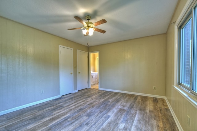 empty room featuring ceiling fan, dark wood-type flooring, visible vents, and baseboards