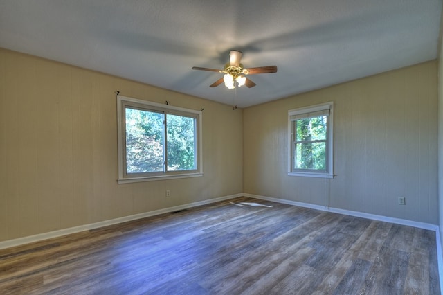 empty room with baseboards, visible vents, dark wood finished floors, and a ceiling fan