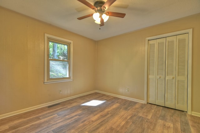 unfurnished bedroom with a closet, visible vents, baseboards, and wood finished floors