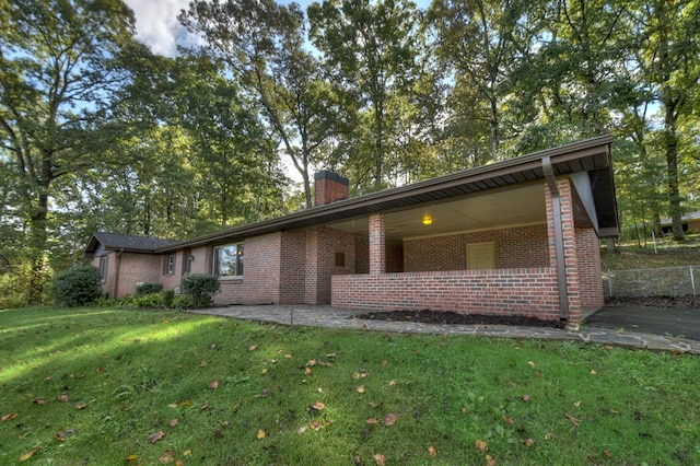 view of front of home featuring a front yard, brick siding, and a chimney