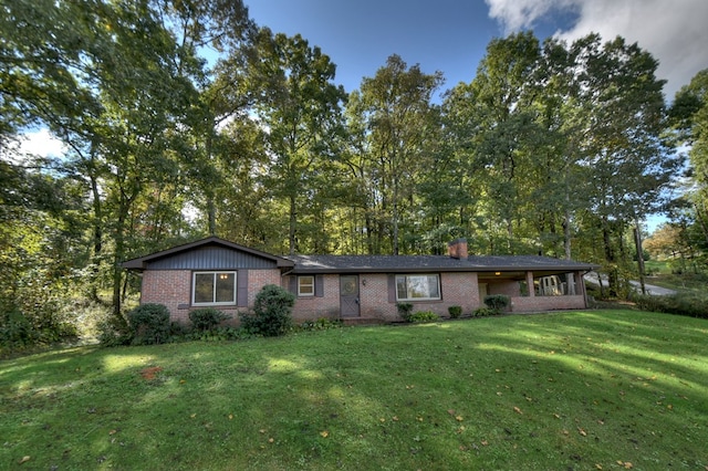 ranch-style home with brick siding, a chimney, and a front yard