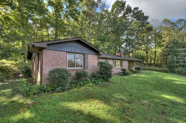 exterior space featuring a chimney, a front lawn, and brick siding