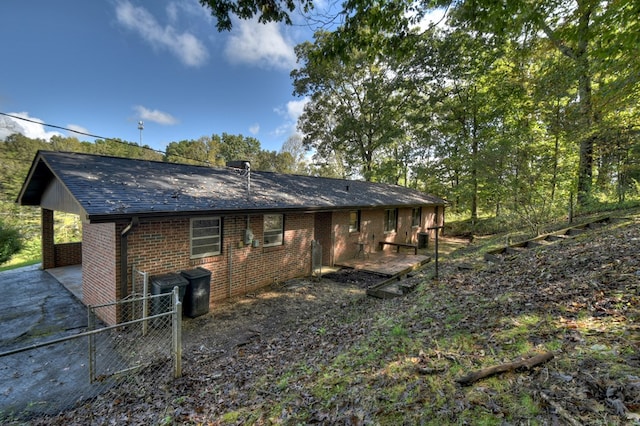 back of property featuring brick siding and roof with shingles