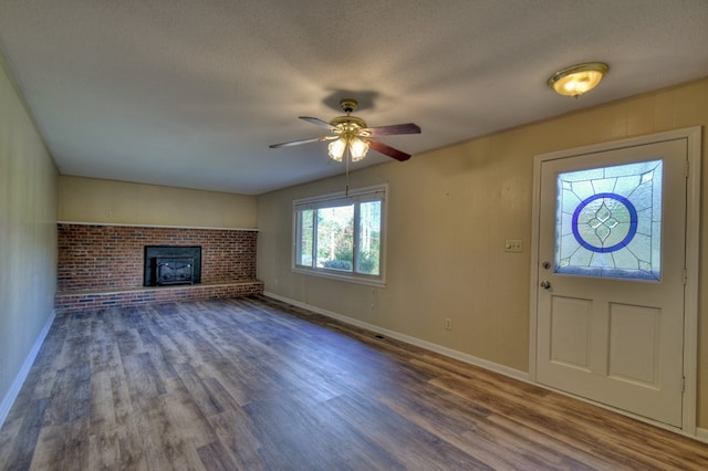 entryway with baseboards, a ceiling fan, wood finished floors, a textured ceiling, and a brick fireplace