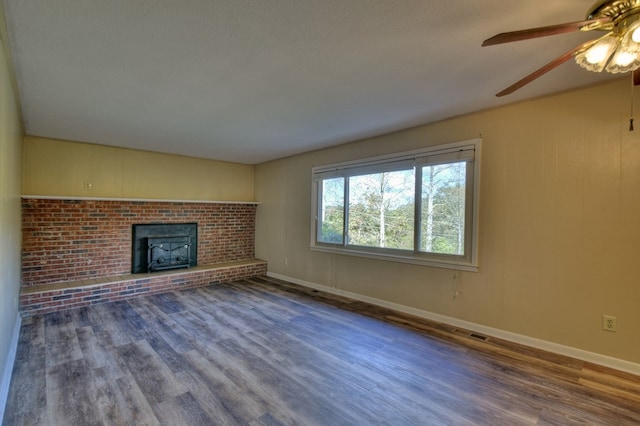 unfurnished living room with a brick fireplace, baseboards, and wood finished floors