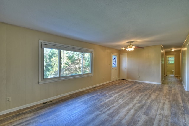 unfurnished room featuring visible vents, a ceiling fan, a textured ceiling, wood finished floors, and baseboards