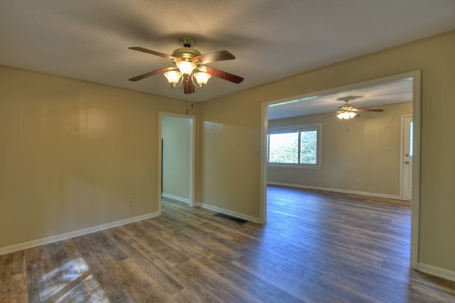 unfurnished room with baseboards, visible vents, a ceiling fan, dark wood-style floors, and a textured ceiling