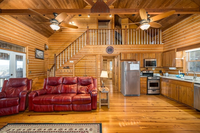 living room featuring sink, wood ceiling, high vaulted ceiling, wooden walls, and beam ceiling