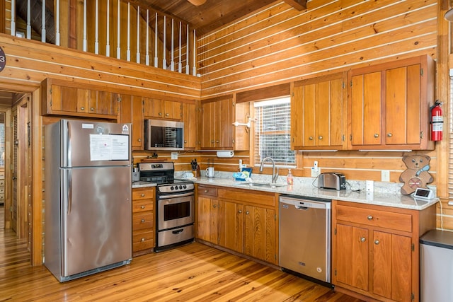 kitchen featuring a high ceiling, appliances with stainless steel finishes, sink, and light wood-type flooring