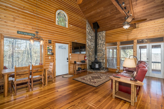 living room with french doors, wood ceiling, high vaulted ceiling, a wood stove, and a wealth of natural light