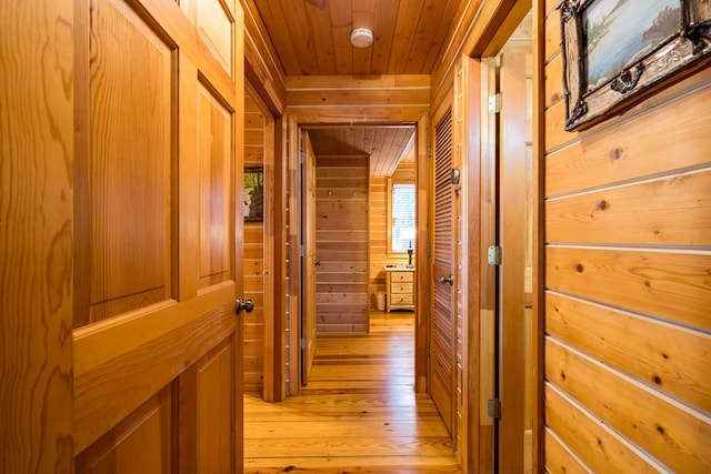 corridor featuring wood ceiling, wooden walls, and light hardwood / wood-style floors