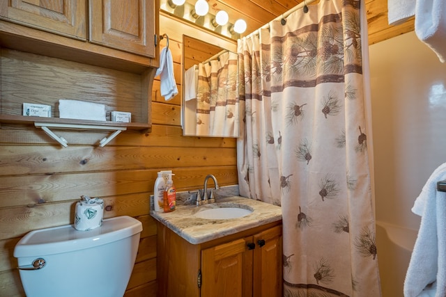 bathroom with vanity, wooden walls, and toilet