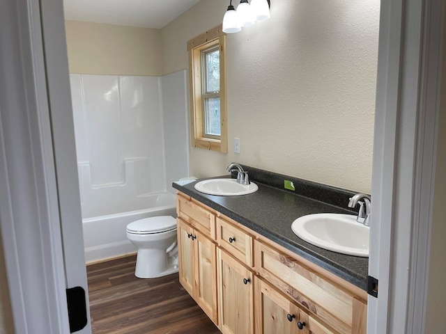 full bathroom with double sink, shower / tub combination, hardwood / wood-style flooring, large vanity, and toilet